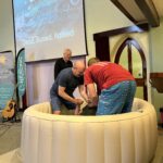 Three people in inflatable baptistry: the candidate, the minister and a helper.